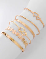 Layered bracelet stack featuring interlocked heart motif