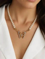 Gold butterfly charm necklace paired with pearl strand