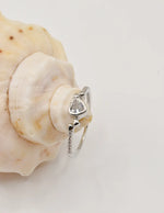 Silver Glow Heart Eternity Ring displayed on a shell, featuring a polished heart gemstone flanked by tiny pavé accents; a minimalist yet romantic gift for her jewellery admired in Montreal jewellery boutiques.