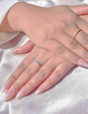 Hand wearing dual-tone crystal wedding band ring on silk fabric