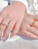 Close-up of two hands wearing rings on a white background