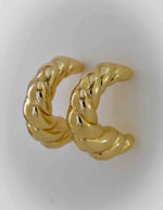 Close-up of modern twisted hoop earrings in gold finish

