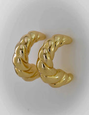 Close-up of modern twisted hoop earrings in gold finish

