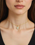 Close-up of dainty gold clover charm with dual finish