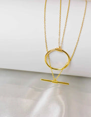 layered bar and circle pendant necklace on white silk background
