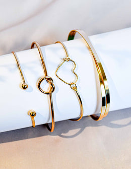 Set of gold charm bracelets with heart and knot details