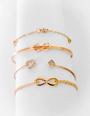 Infinity charm bracelet in gold paired with heart ring and chain