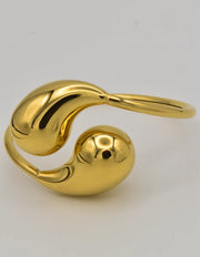 Teardrop gold bracelet bangle resting open on white background