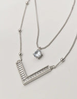 dainty silver initial necklace v pendant close-up on textured background
