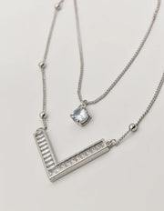 dainty silver initial necklace v pendant close-up on textured background