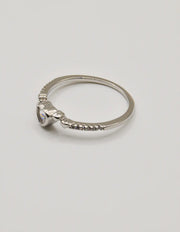 Angled shot of the Silver Glow Heart Eternity Ring on a seashell, showing the heart‑shaped centre stone and elegant pave setting; a clean girl jewellery 2025 favourite and thoughtful gift for her jewellery